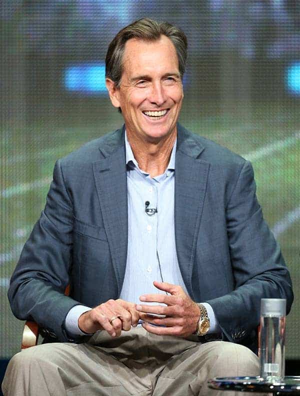 Cris Collinsworth smiling in gray coat white shirt on tv interview 