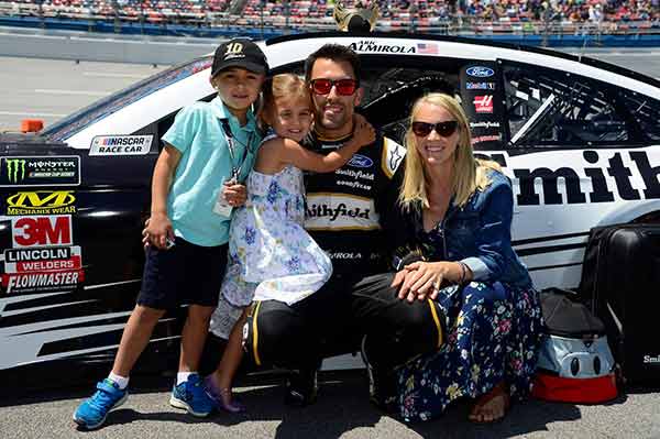 Image showing happy couple alongside their kids enjoying quality time together outside racetrack environment altogether!